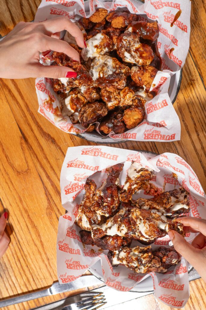 pexels-photo-31228737-31228737 Sizzling hot chicken wings served in baskets with hands reaching in for a tasty bite.